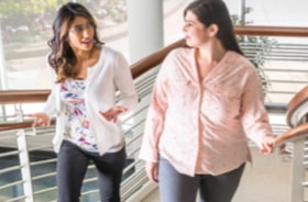 Two women climbing well-lit staircase while having a conversation