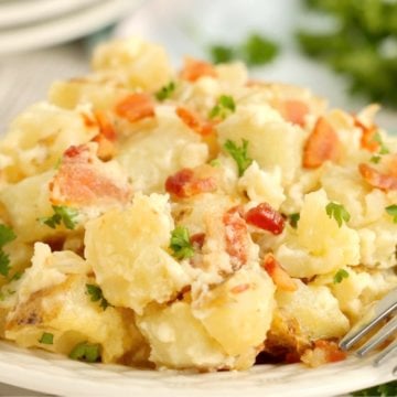 A close up of cooked potatoes and bacon on a plate