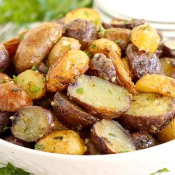 White bowl filled with roasted, sliced potatoes.