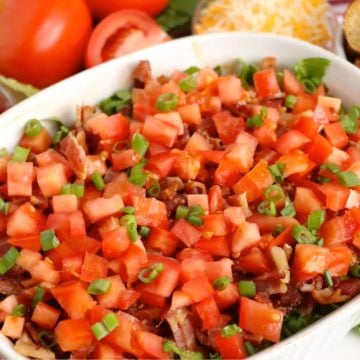 Hot BLT dip in a white dish, layered with bacon, lettuce, and tomatoes.