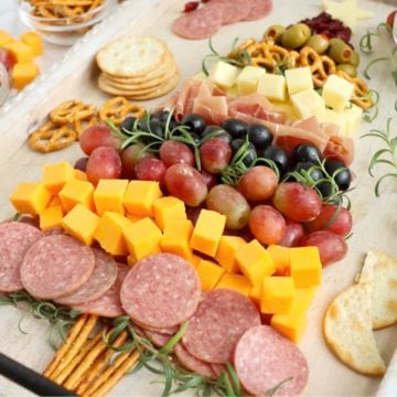 Christmas-themed charcuterie board arranged with meats, cheeses, and pretzels in a tree shape.