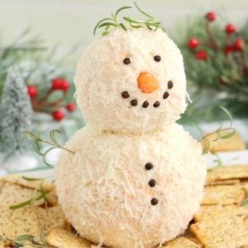 Cute snowman cheeseball appetizer surrounded by crackers.