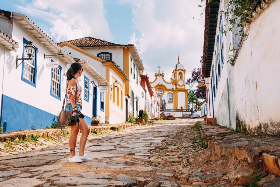 Na foto esta uma mulher em uma ladeira de tiradentes. Um dos destinos para casais mais românticos do Brasil e ideal para o Dia dos Namorados