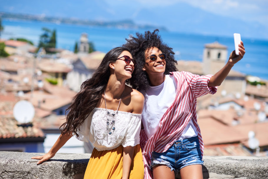 Na imagem estão duas mulheres viajantes lado a lado ilustrando como encontrar companhia para viajar