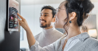 Woman uses smart device to set the temperature while her partner watches