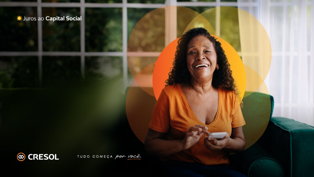 Mulher sentada sorrindo com o celular na mão