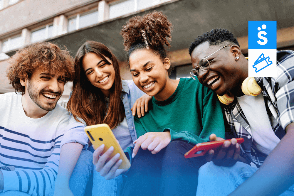 Grupo com quatro pessoas sorrindo e olhando para o celular