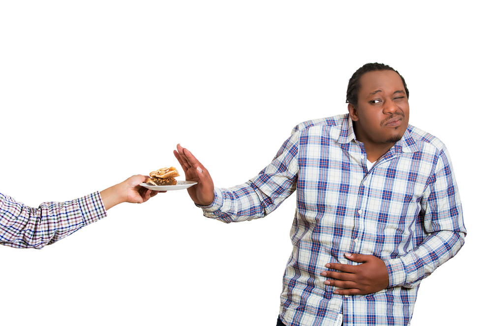 Closeup portrait sad, young, confused, funny looking man trying to withstand, deny, resist temptation to eat offered sweet cake, tart, isolated white background. Facial expression, emotions, reaction