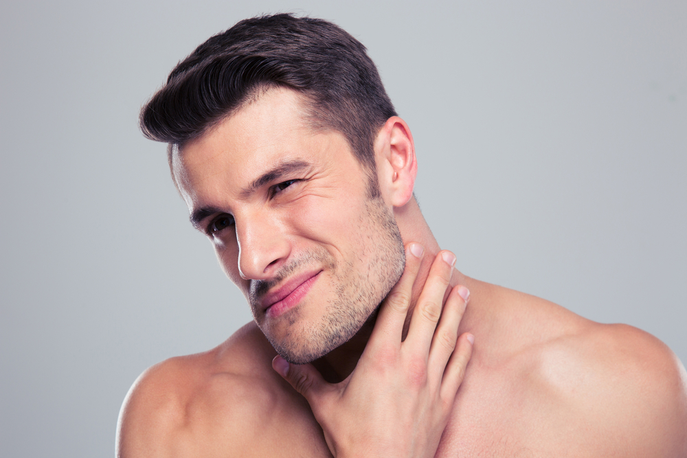 Portrait of a handsome man with neck pain over gray backgorund