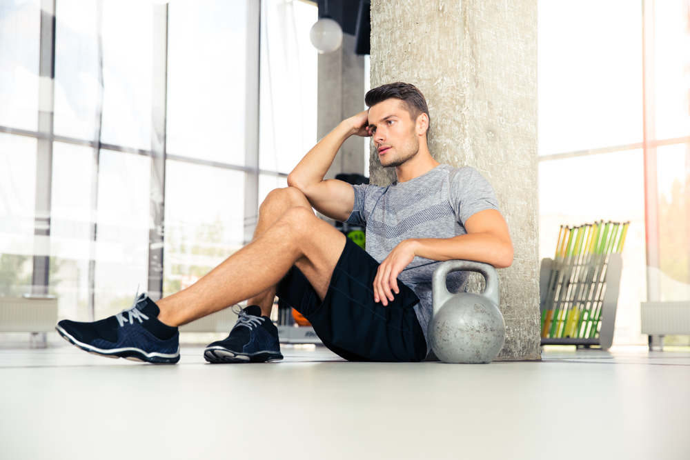 Portrait of a tired fitness man resting at gym