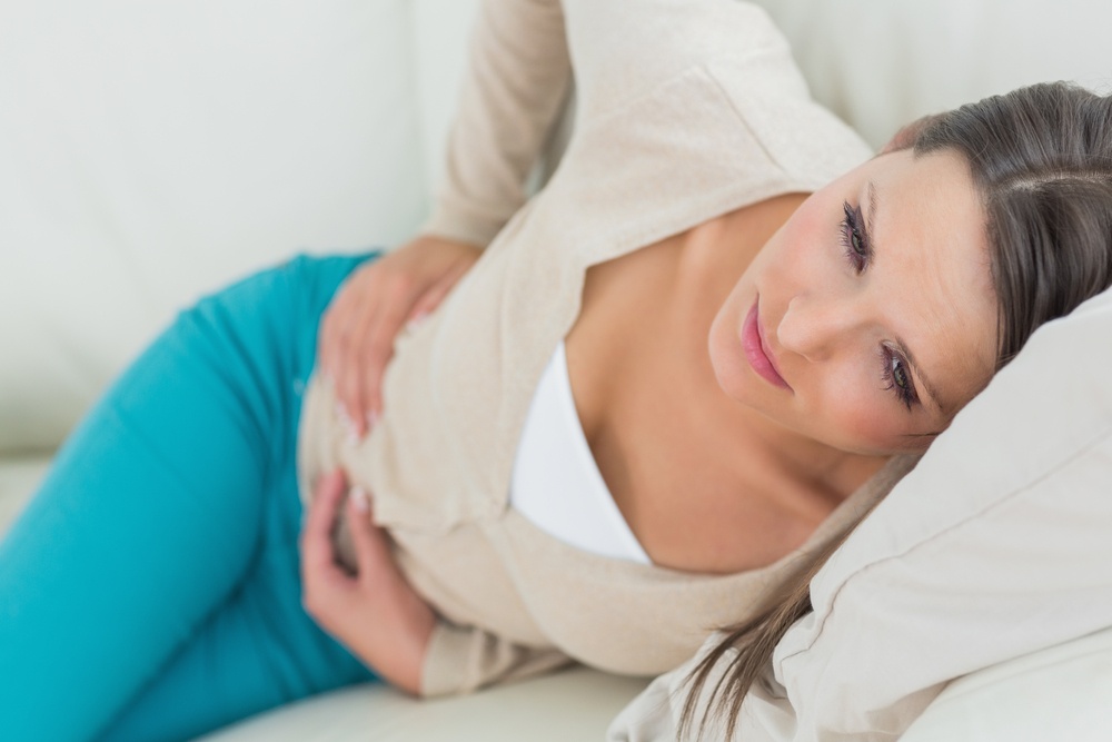 Woman lying on sofa looking sick in the living room