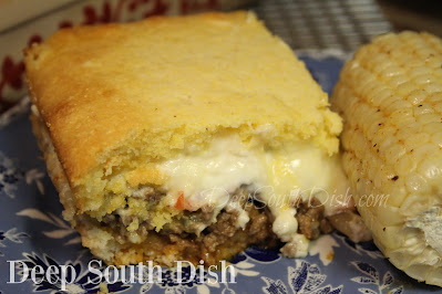 A Tex-Mex style casserole with seasoned ground beef, layered between a biscuit crust, with tomatoes, topped with a sour cream and cheese sauce and finished with a cornbread topping, perfect for potlucks, church suppers, or just dinner at home!