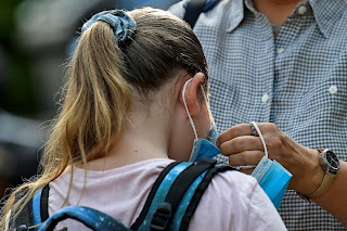 Une étudiante fait préparer son masque facial par sa mère dans une école de Gelsenkirchen, en Allemagne, le 12 août 2020. | Martin Meissner / AP Photo