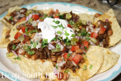 Tortilla chips, covered in shredded beef, seasoned pinto beans and white cheese, and finished with your favorite garnishes.