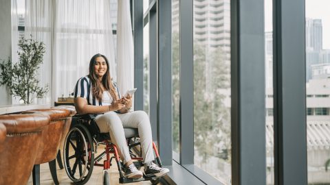 Woman using a wheelchair holding a tablet.