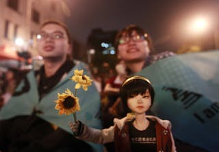 Activists take part in a sit-in to mark the one-year anniversary of the start of the Sunflower Movement outside the Legislative 