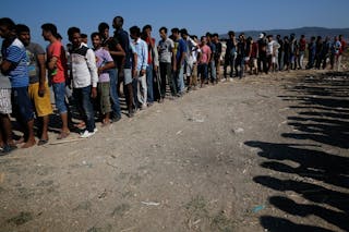 Migrants line up to receive sandwiches offered by volunteers of the organisation "Solidarity Kos" outside Captain Elias, a derel