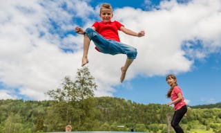 Two scandinavian kids playing and having fun while jumping on large inflatable bouncing pillow.