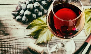 red wine and grapes. Wine and grapes in vintage setting with corks on wooden table