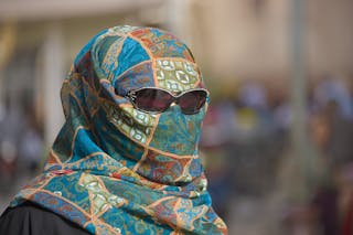 Uighur woman in sunglasses with face and hair covered