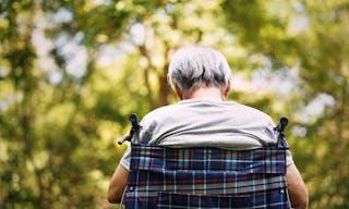 rear view of a senior man sitting in wheelchair with head down