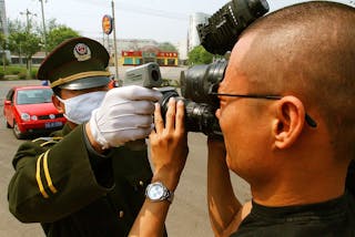 GUARD CHECKS TEMPERATURE OF JOURNALIST