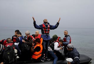 敘利亞難民＿A Syrian refugee gives thanks to God as he arrives in an overcrowded dinghy on the Greek island of Lesbos after crossing p