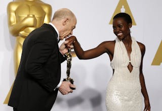 Simmons, winner of the award for best supporting actor nominee for his role in "Whiplash," kisses the hand of presenter Lupita N