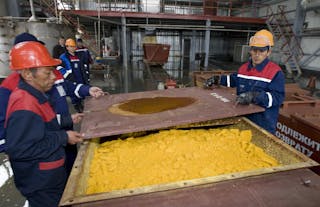 Workers close container of uranium oxide after opening of the Khorasan-1 uranium mine in southern Kazakhstan