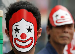 Demonstrators wearing masks depicting the mascot of McDonald's take part in a protest to demand higher wages for fast-food worke