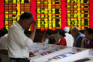 Investors look at computer screens showing stock information at a brokerage house in Shanghai