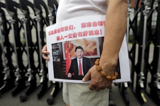 A man holds a placard with a picture of China's President Xi Jinping during a protest in Beijing