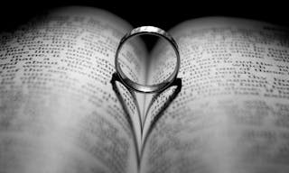 Wedding Ring and heart shaped shadow over a Bible