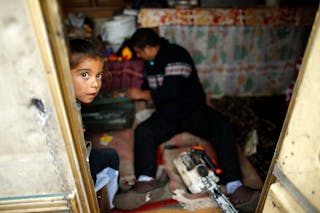 A girl is seen at the door of a caravan at an encampment of Roma families in Triel-sur-Seine, near Paris