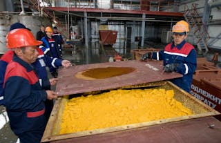 Workers close container of uranium oxide after opening of the Khorasan-1 uranium mine in southern Kazakhstan