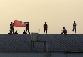 Spectators on a rooftop hold up the Taiwan flag during the annual Han Kuang military exercise in Chiayi County