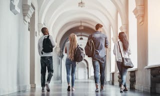 Multiracial students are walking in university hall during break and communicating.