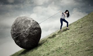 Image of young businesswoman climbing on the hill while pulling big stone with a chain - 圖片