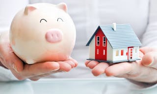 Hands holding a  piggy bank and a house model. Housing industry mortgage plan and residential tax saving strategy