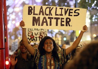 A protestor marches with a sign after a gathering to show solidarity with the family of black teenager Michael Brown outside the