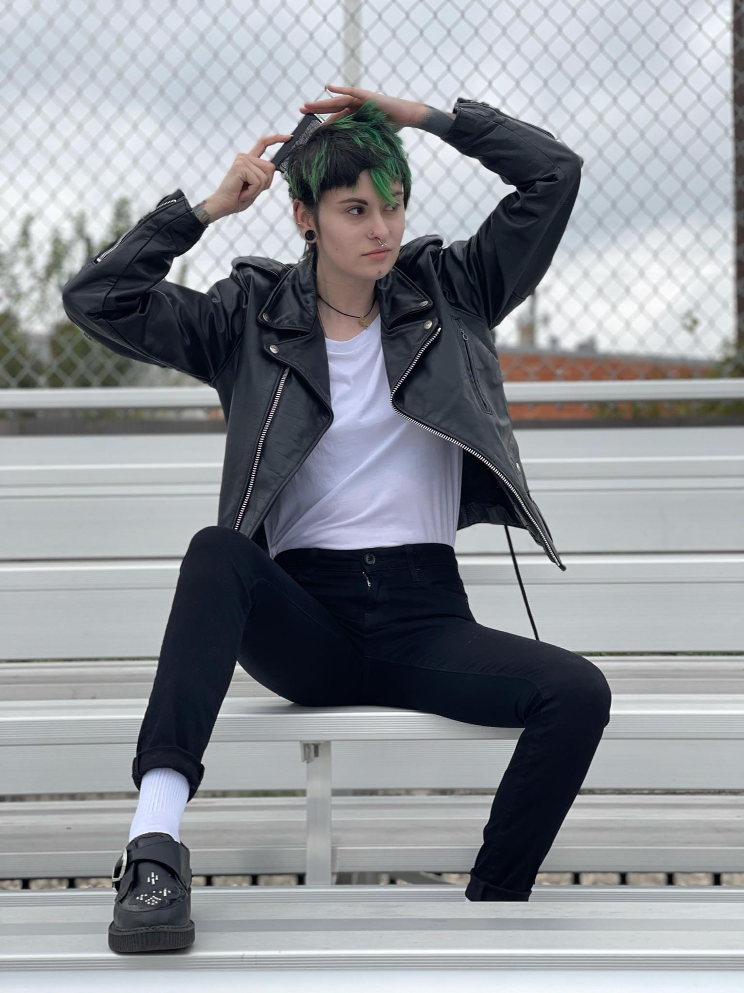 Person sitting on bleachers combing hair and dressed as Danny Zuko from Grease