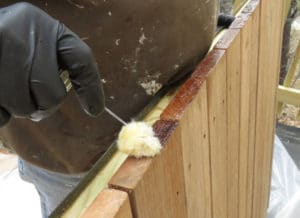 Installer applies end-grain sealer to prevent cracks in hardwood decking.