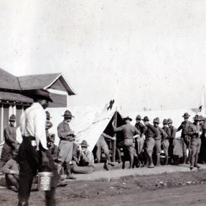 White soldiers in uniforms at camp with house and row of tents