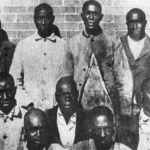 Group of African-American men standing and sitting before brick wall