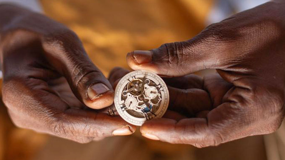 A close-up shot of Bala Muhammad's hands holding the insides of a wrist watch