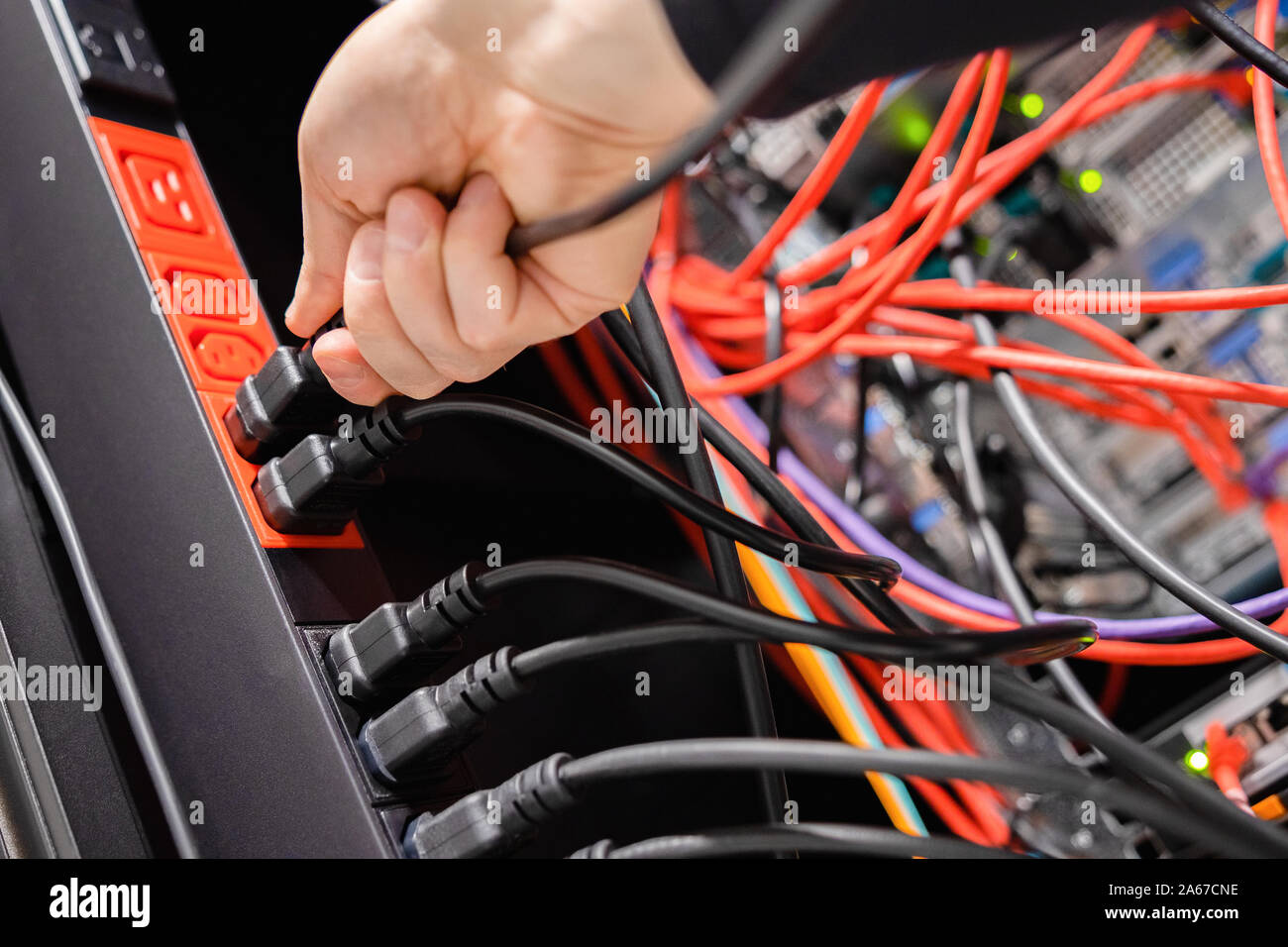 Male IT Engineer Removing Power Cable From Outlet in Datacenter Stock Photo