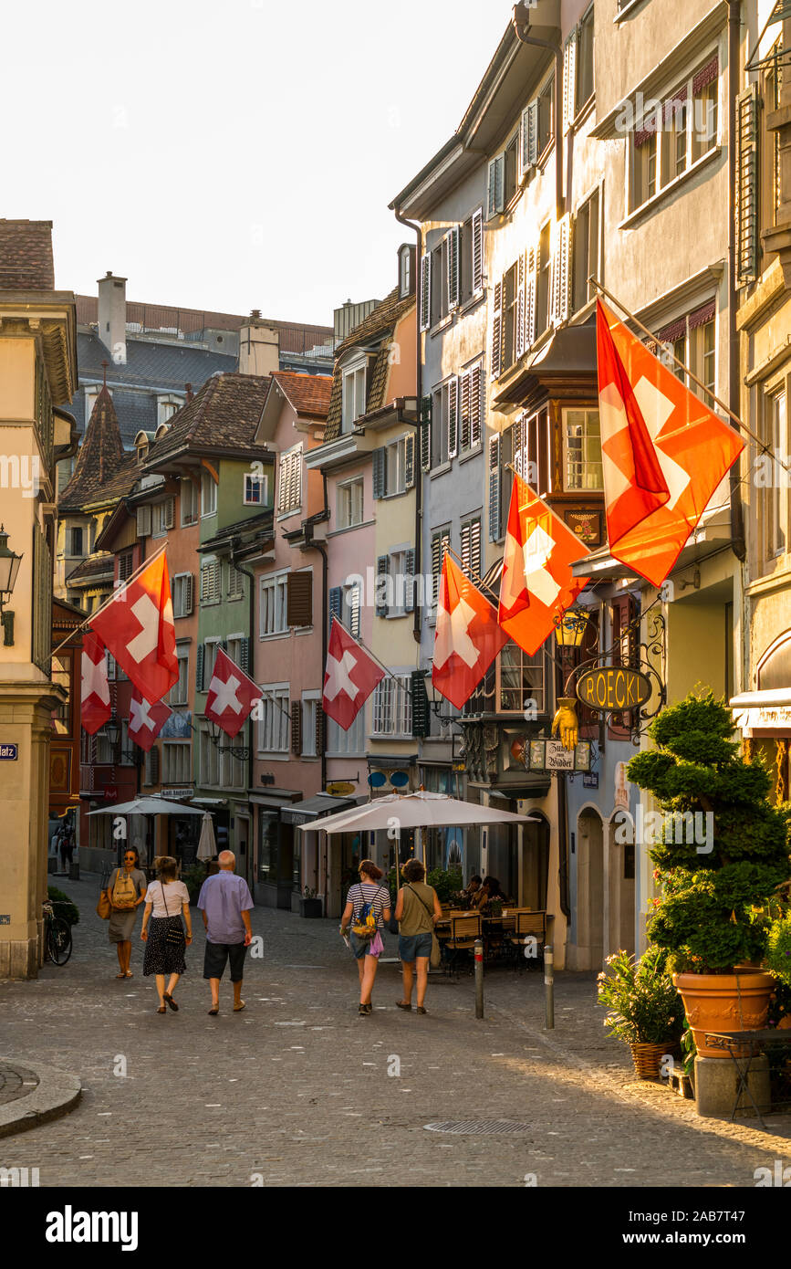 Tourists look at the Swiss flags hanging from buildings in Lindenhof, Zurich, Switzerland, Europe Stock Photo