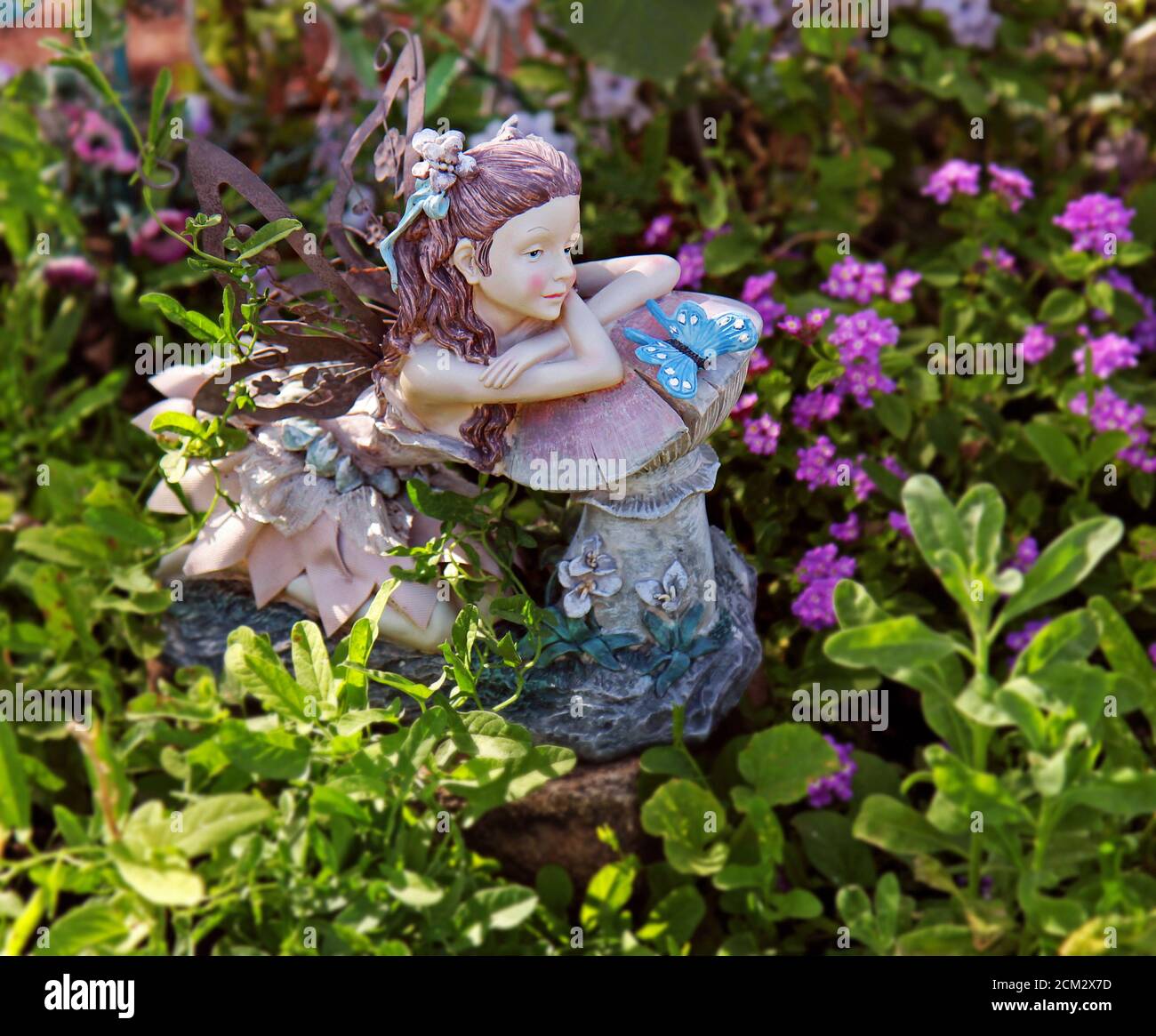 A fairy figurine graces a small garden. Stock Photo