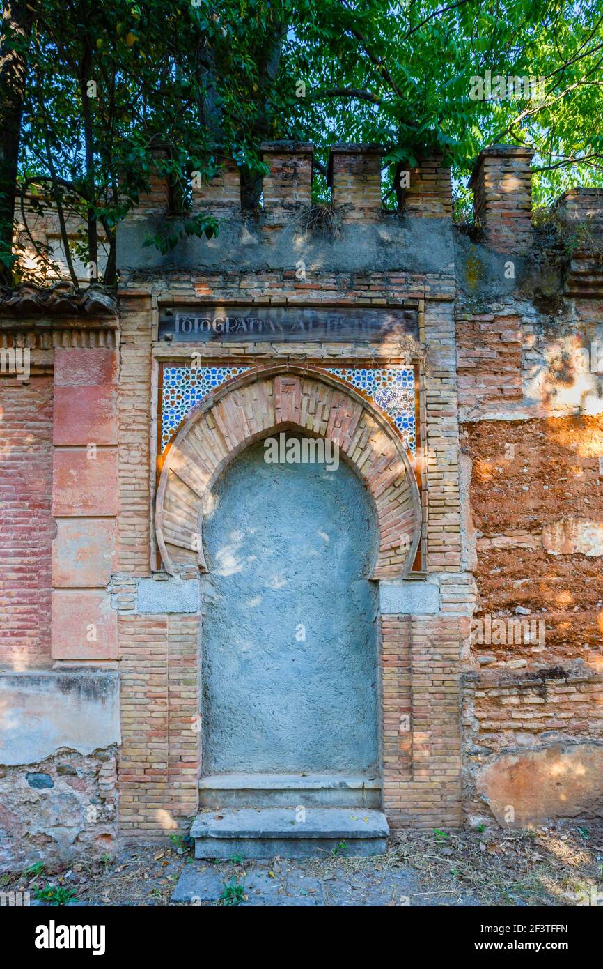 Arched doorway and closed entrance in a roadside redbrick wall with crumbling brickwork near the Alhambra y Generalife, Granada, Andalusia, Spain Stock Photo