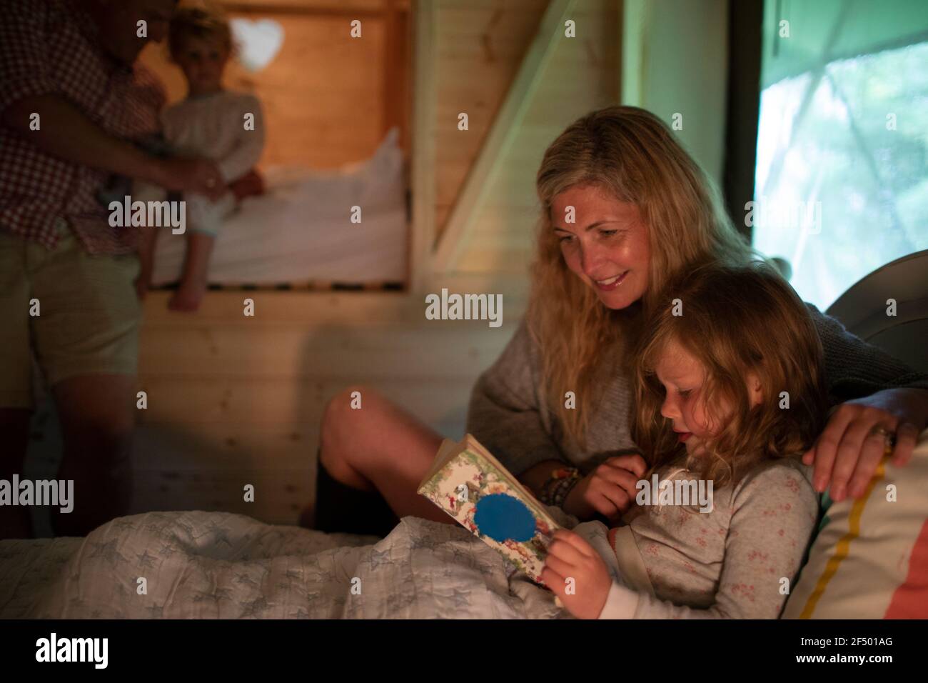 Mother and daughter reading bedtime story book in bed Stock Photo